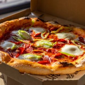 Tasty Neapolitan pizza with fresh ingredients in a cardboard box, perfect for takeout.